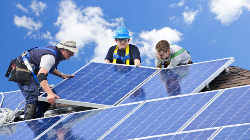 une équipe d'ouvrier qui installe des panneaux solaires sur le toit d'une maison